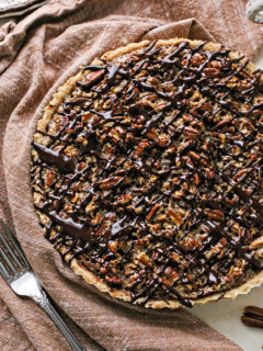 photo of a chocolate pecan tart recipe drizzled in chocolate ganache