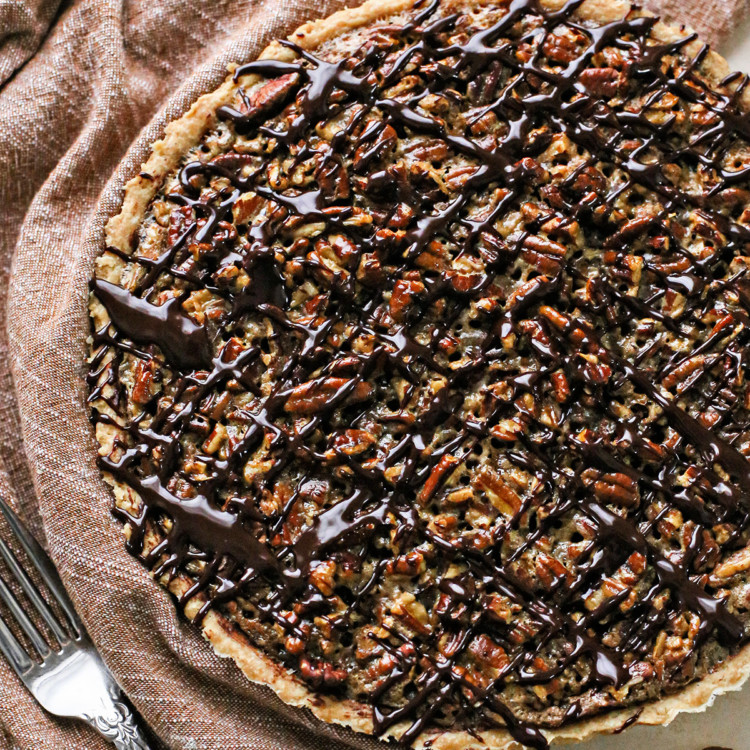 photo of a chocolate pecan tart recipe drizzled in chocolate ganache