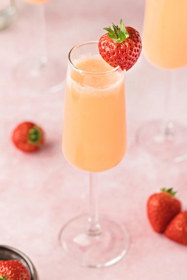 photo of a strawberry mimosa in a champagne flute with a fresh strawberry garnish
