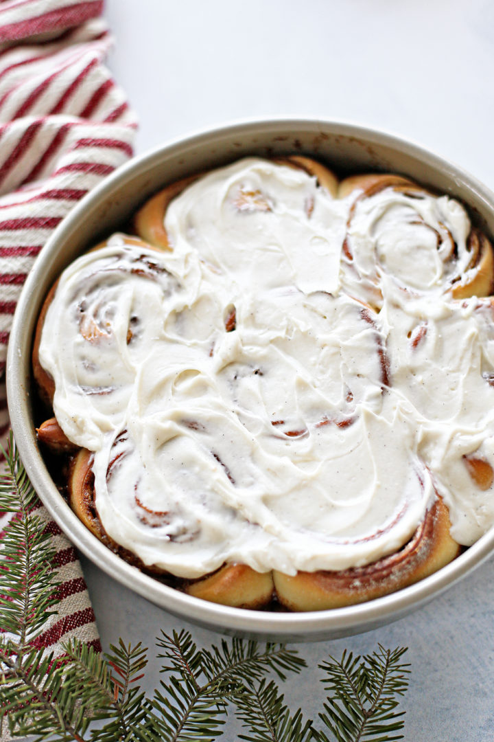 photo of the best homemade cinnamon roll recipe with cream cheese frosting on them in a round baking pan