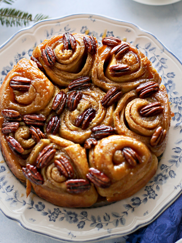 photo of pecan rolls on a plate set at a table next to a mug of coffee