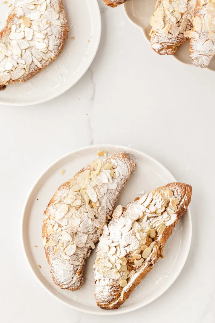 photo of two almond croissants on a white plate on a marble background