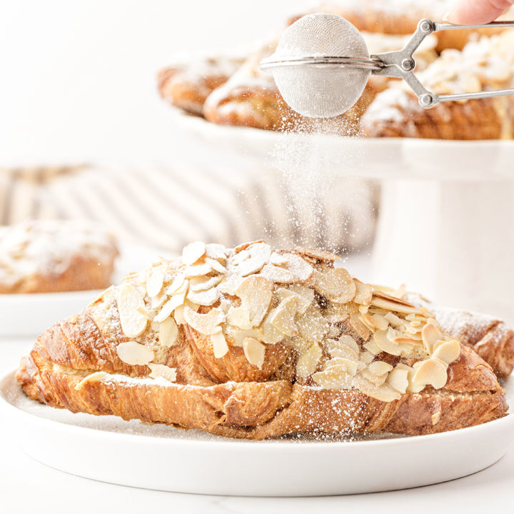 photo of this recipe for almond croissants being dusted with powdered sugar