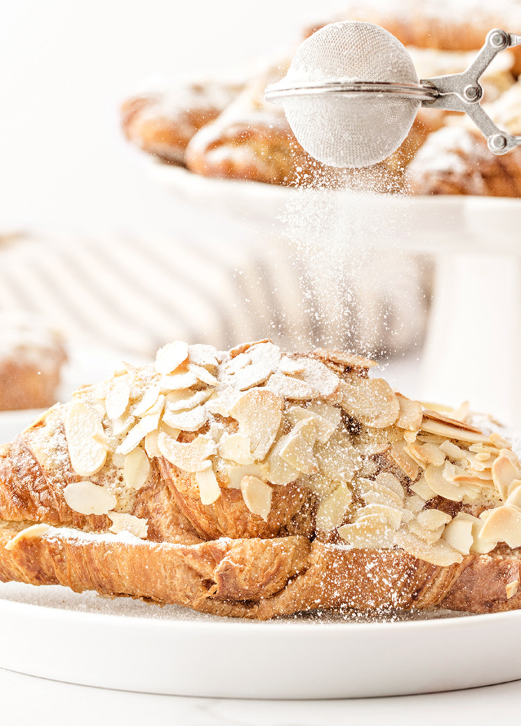 photo of this recipe for almond croissants being dusted with powdered sugar