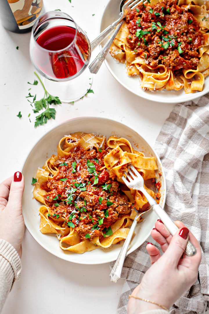 woman eating a bowl of pasta with the best bolognese sauce