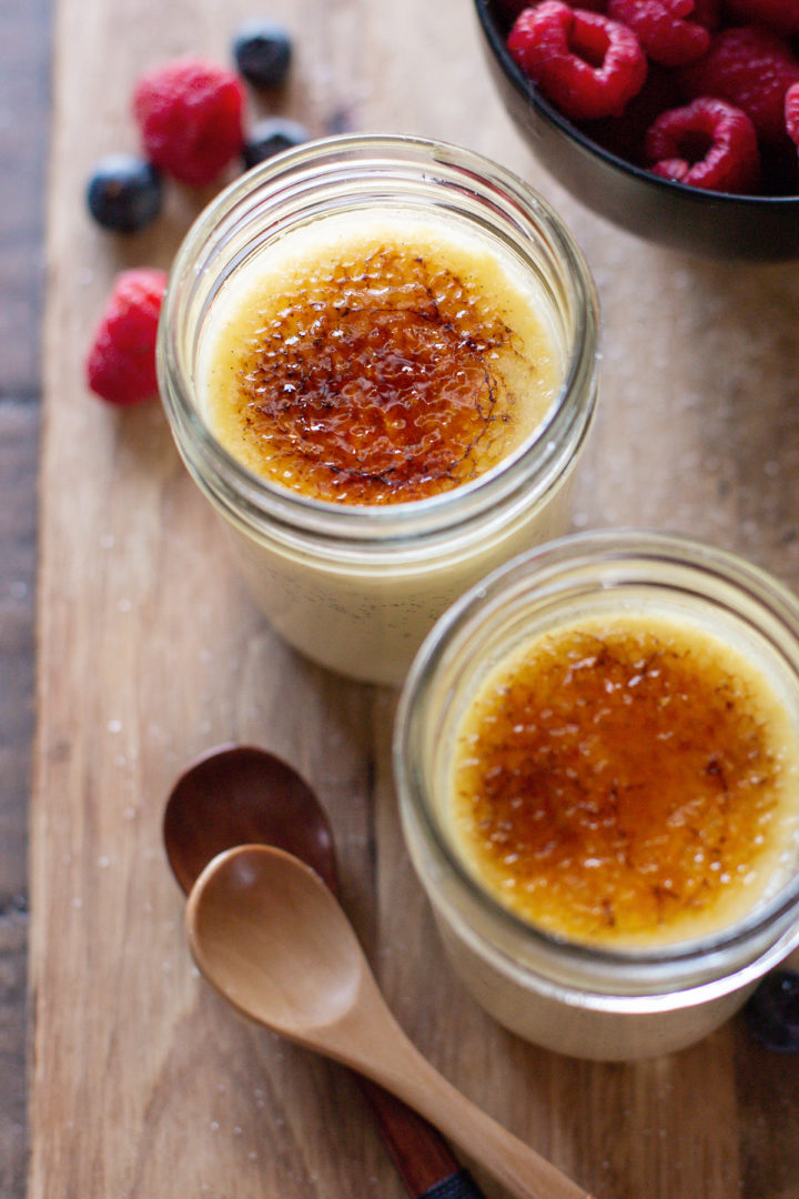 close up photo of sous vide creme brulee cooked in jars on a wooden cutting board with spoons