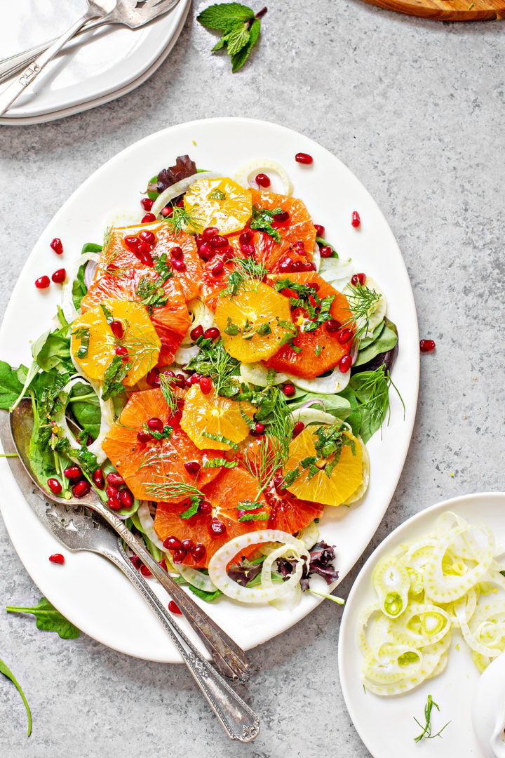 fennel and orange salad on a large white serving platter on a table with salad plates and silverware