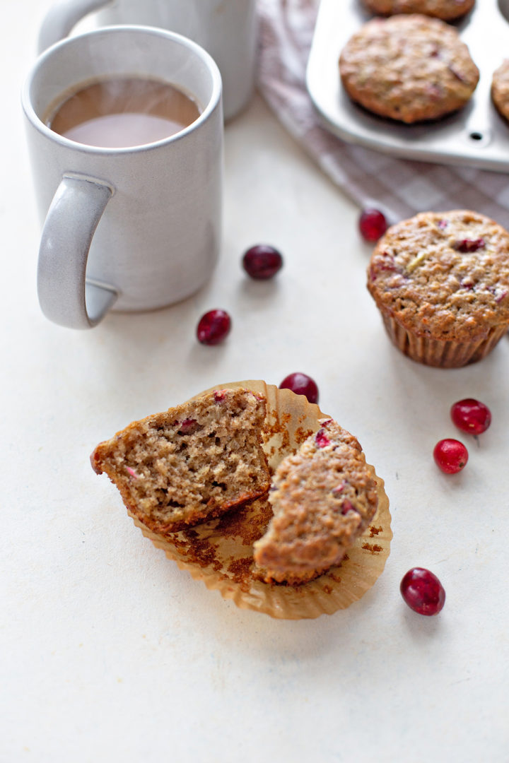 coffee cup next to a cranberry muffin on a kitchen counter