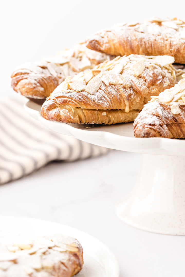 photo of a batch of almond croissants on a white cake stand