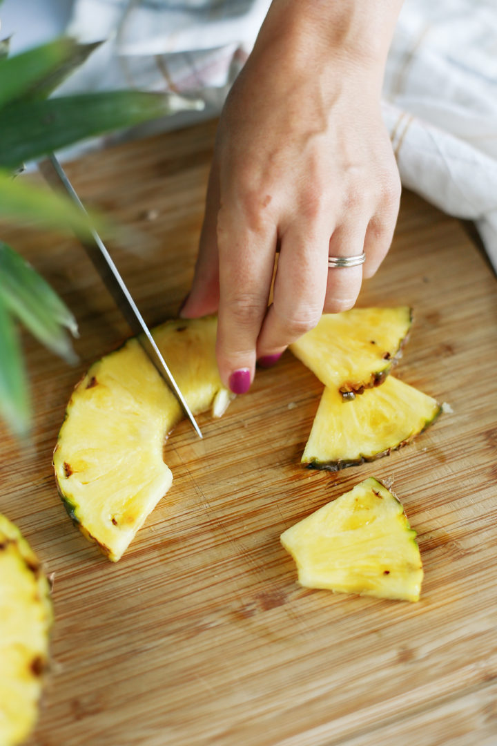 woman showing how to cut a pineapple in wedges