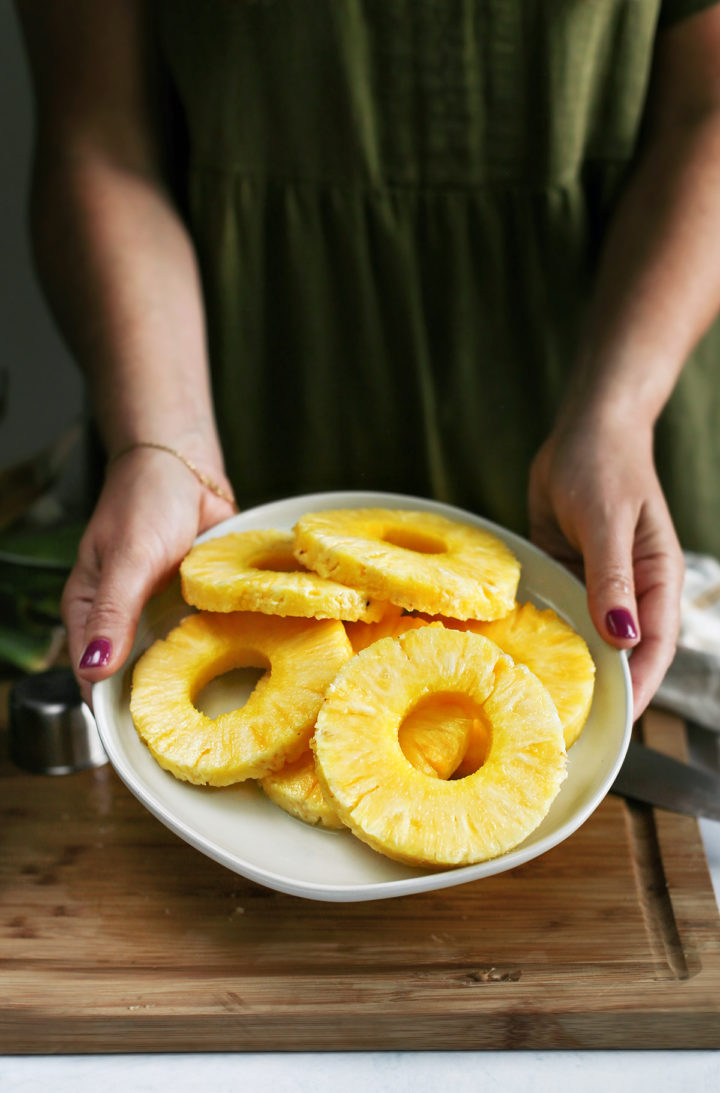 woman holding a plate of freshly cut pineapple