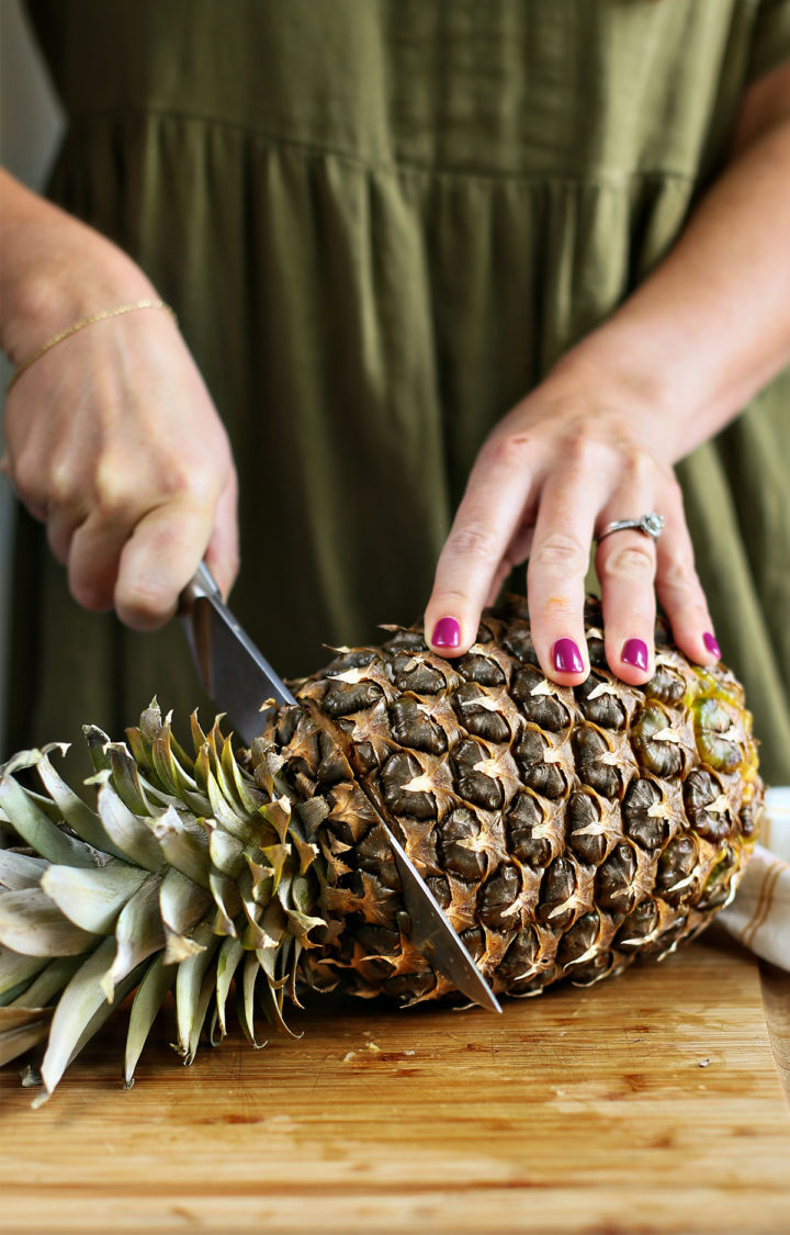 woman cutting the top off a pineapple for a pineapple cutting tutorial