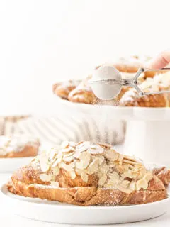photo of this recipe for almond croissants being dusted with powdered sugar