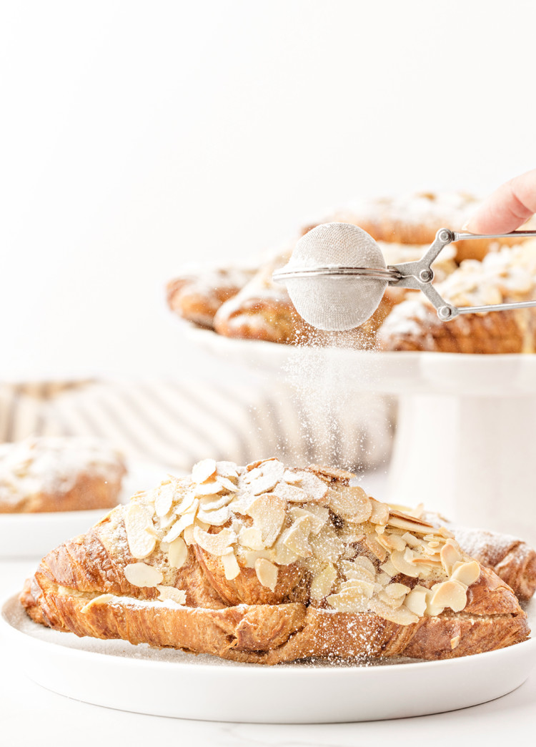 photo of this recipe for almond croissants being dusted with powdered sugar