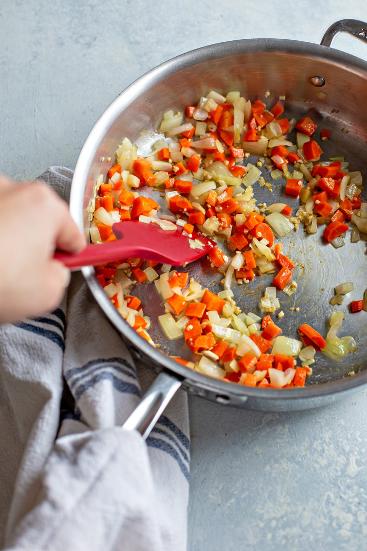 photo of woman sauteeing carrots and onion for this potato and ham soup recipe