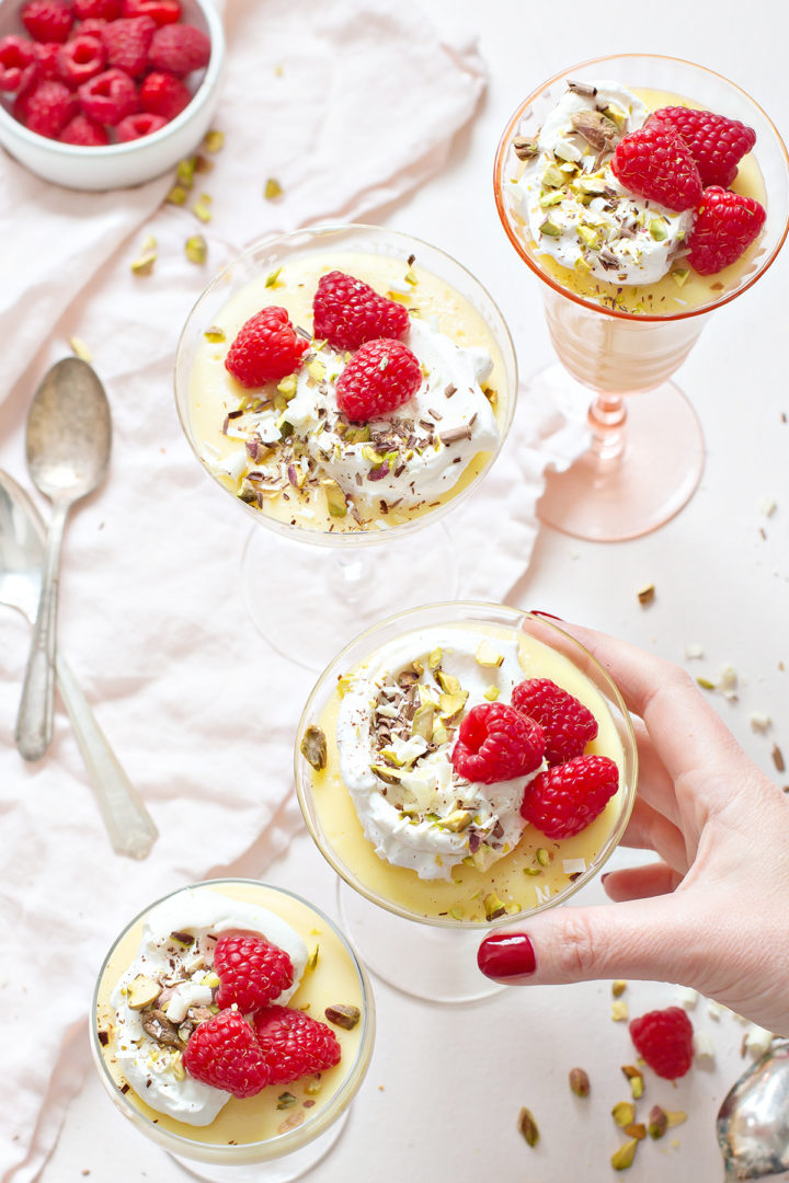 woman holding a glass dessert bowl of white chocolate pudding