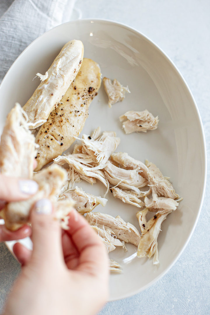 photo of a woman showing how to shred chicken