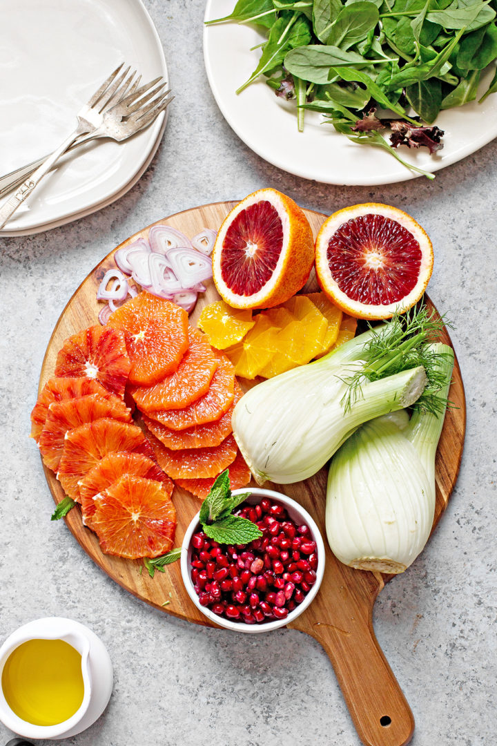 ingredients needed to make fennel and orange salad on a wooden cutting board