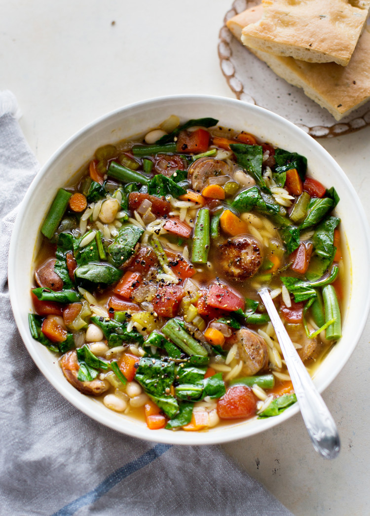 a white bowl filled with italian sausage soup with orzo