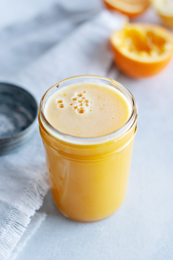 photo of orange curd in a jar next to fresh oranges