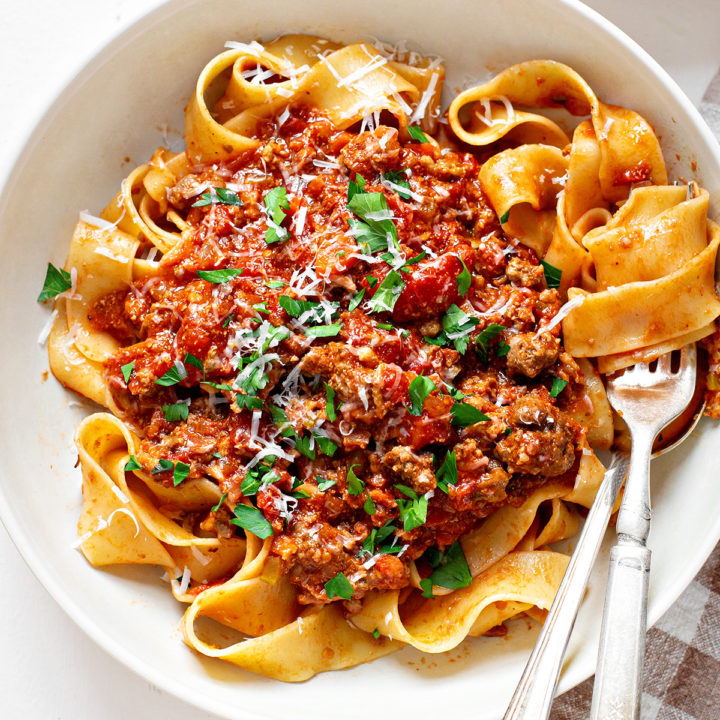 photo of bolongese sauce on pasta in a white bowl