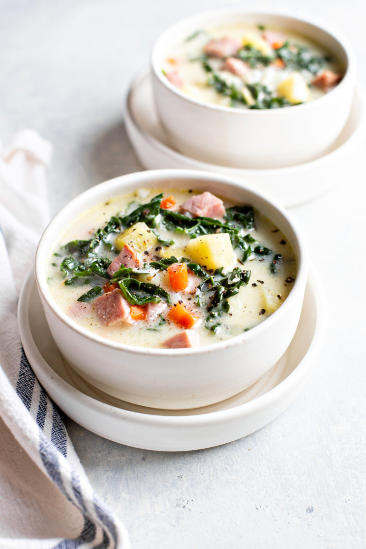 photo of a table with two white bowls with ham bone soup in them