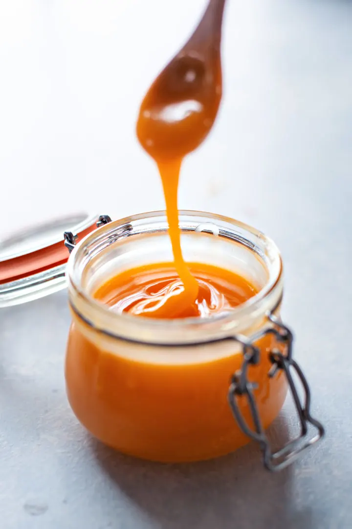 Grapefruit curd drizzling into a jar off of a spoon