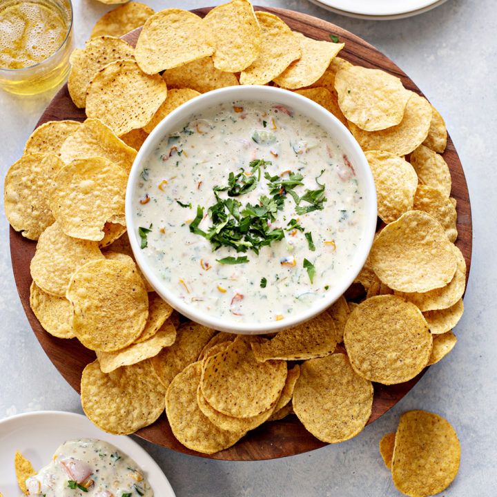 overhead photo of a bowl of queso blanco surrounded by chips on a table