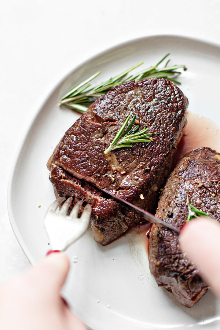 woman cutting into a sous vide steak with a knife on a white plate