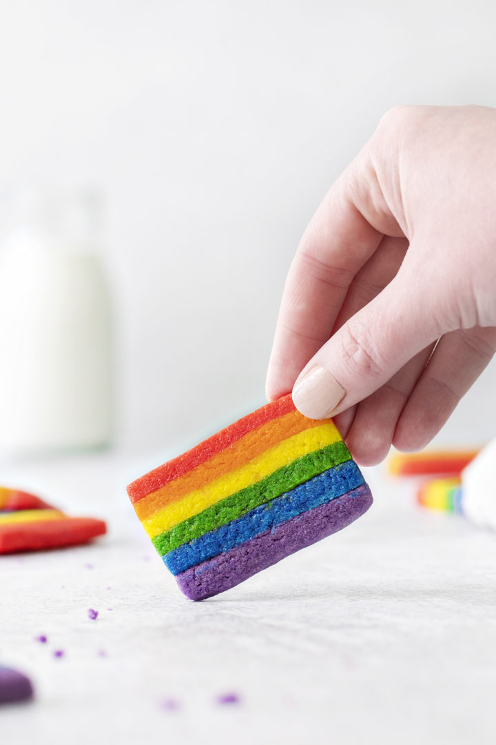 woman holding a rainbow cookie