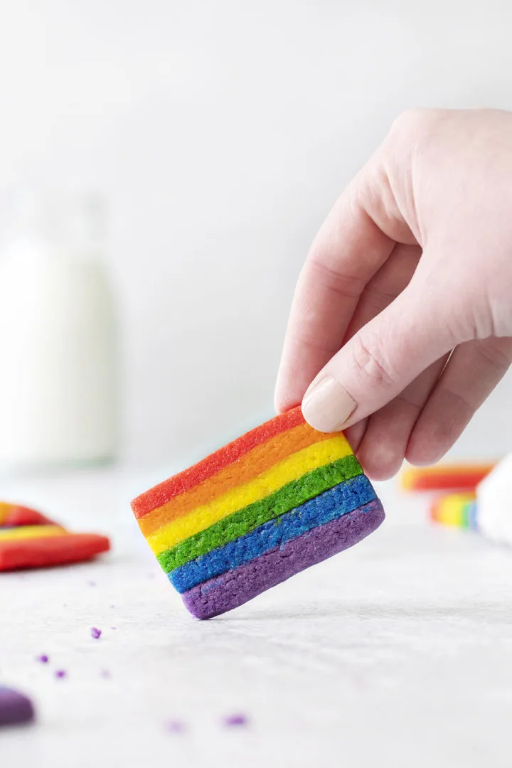 woman holding a rainbow cookie
