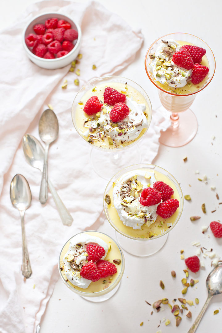 overhead photo of a table set with dessert glasses full of white chocolate pudding topped with garnishes