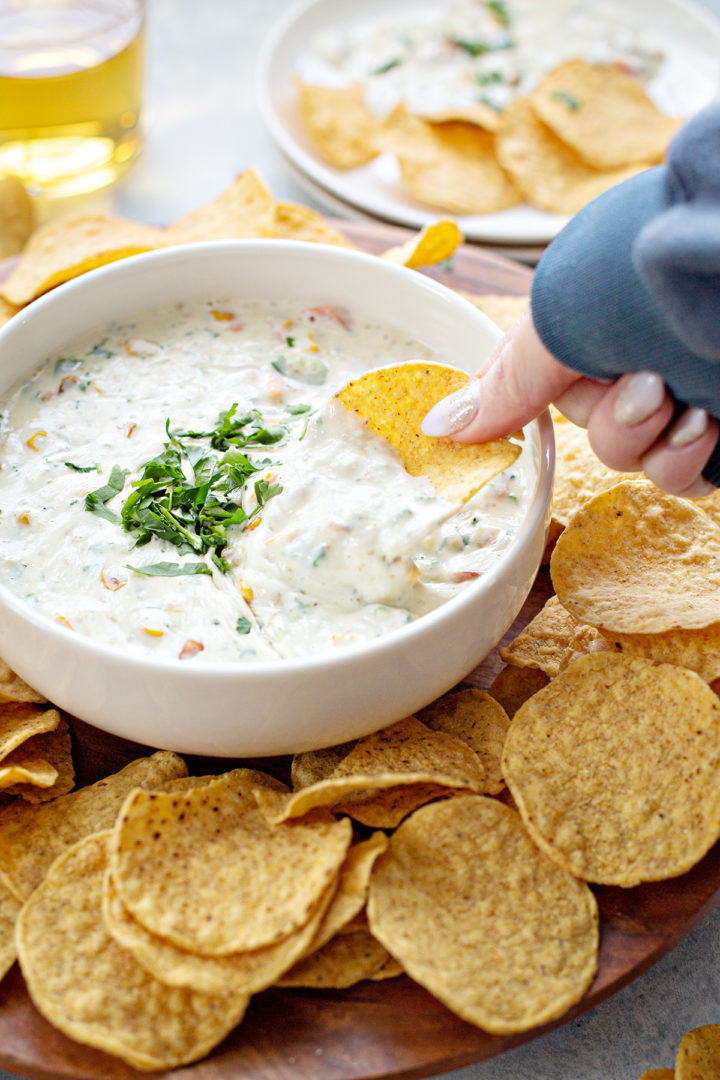 woman dipping chips in a bowl of queso blanco 