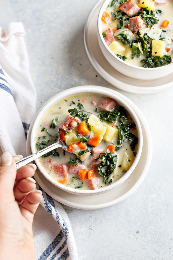 photo of a woman eating ham soup from a white bowl full of ham and potato soup