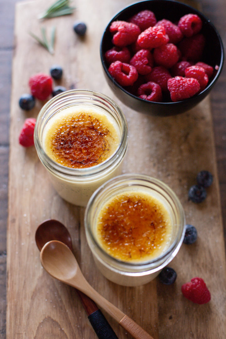 photo of 2 jars of Sous Vide Crème Brûlée on a wooden cutting board with fresh berries