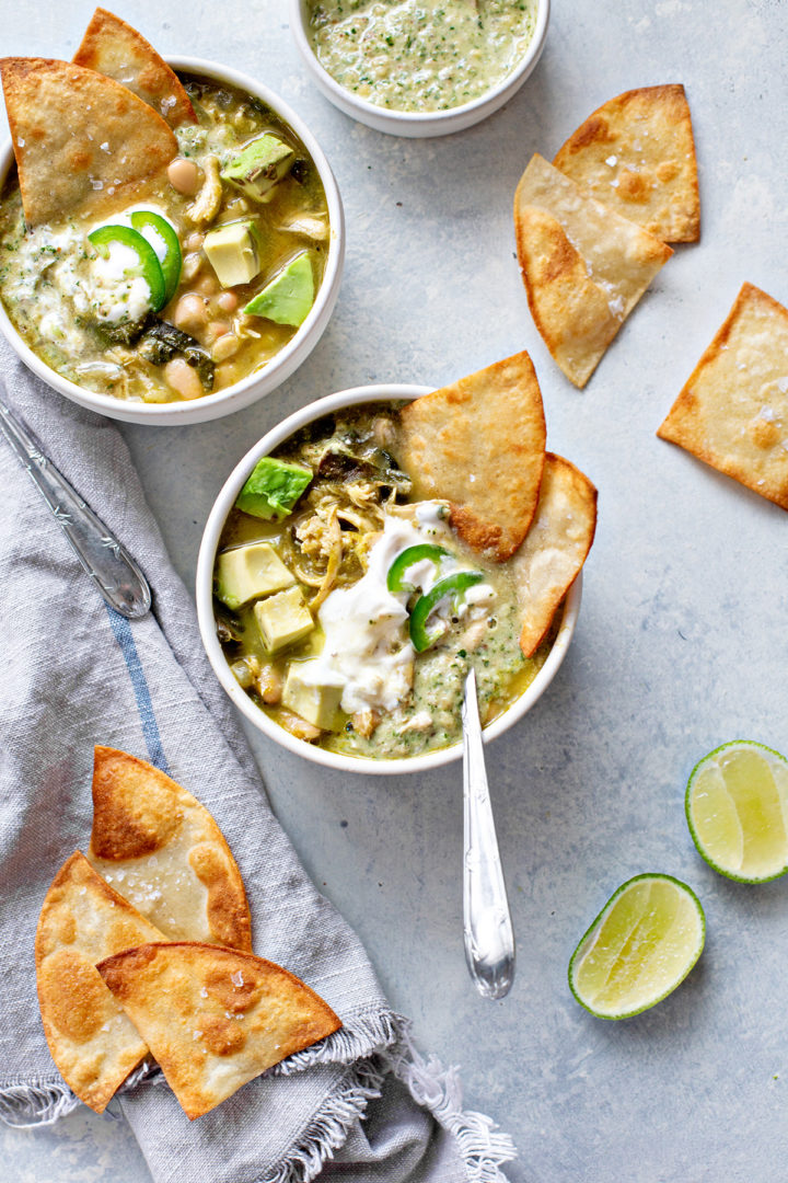 servings of chili verde chicken on a table with limes and tortilla chips