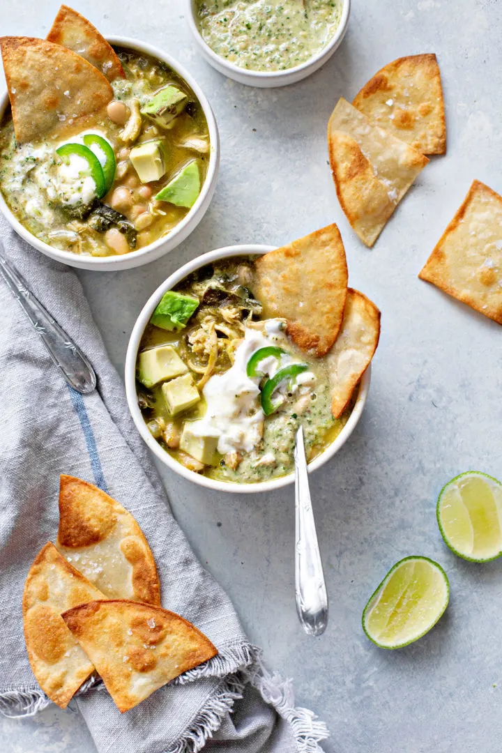 whitebeanchiliverde servings of chili verde chicken on a table with limes and tortilla chips