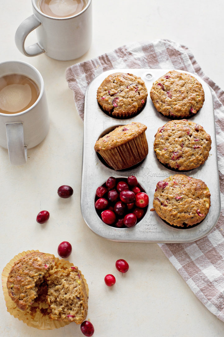 photo of cranberry muffins in a muffin tin with fresh cranberries