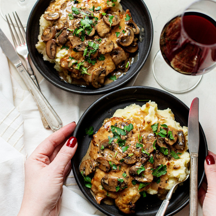 woman setting a plate of chicken marsala