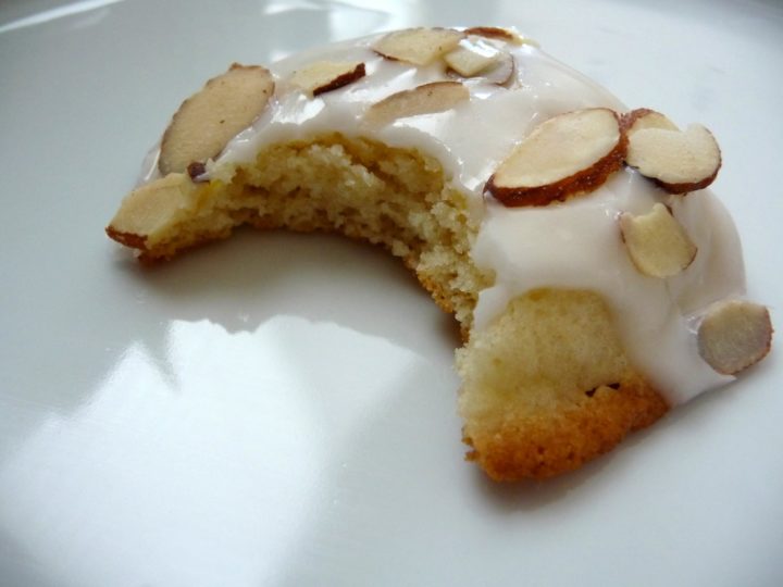 buttermilk cookie with lemon glaze and sliced almonds on a white plate