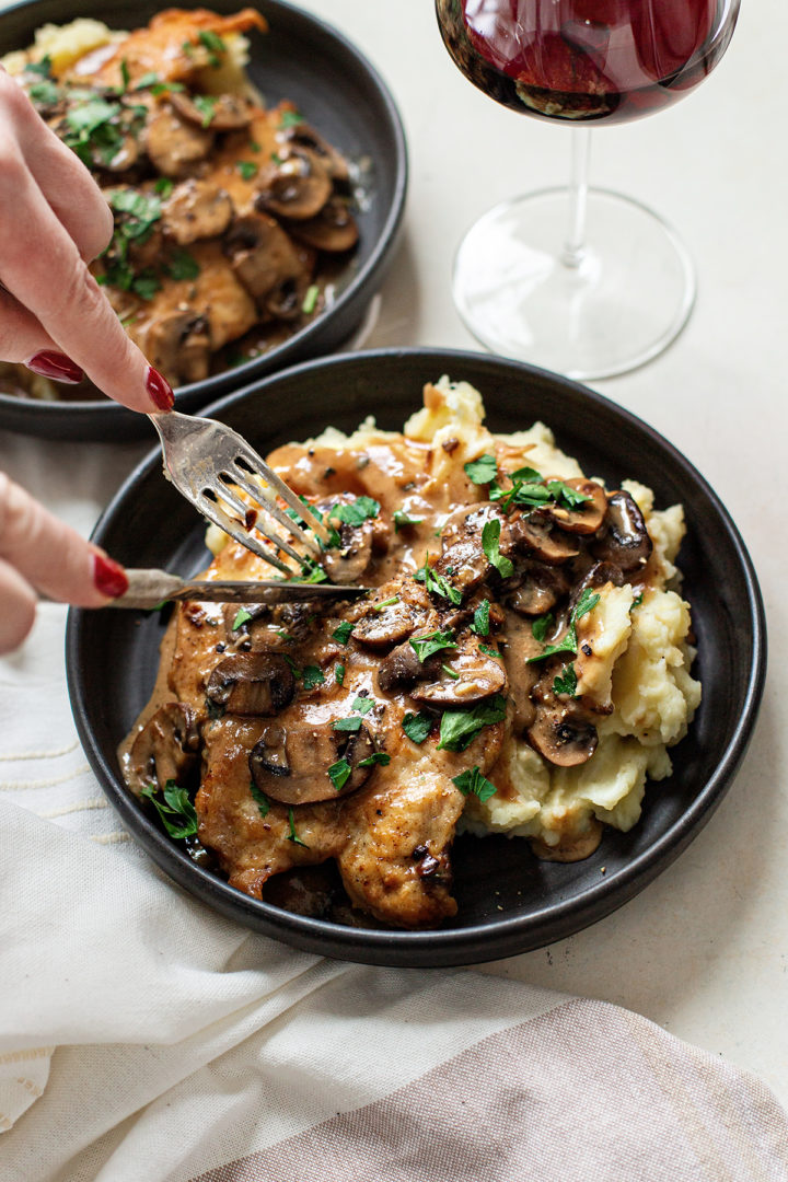 woman cutting into a piece of chicken marsala