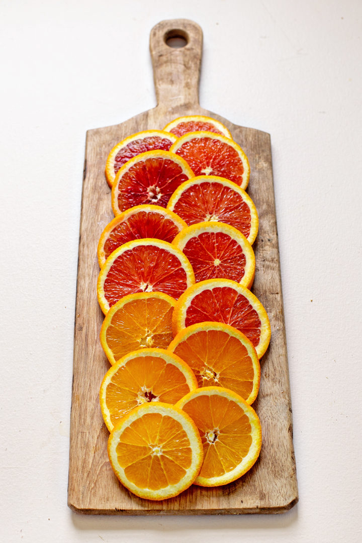 sliced citrus fruits on a wooden cutting board to use for making a citrus salad