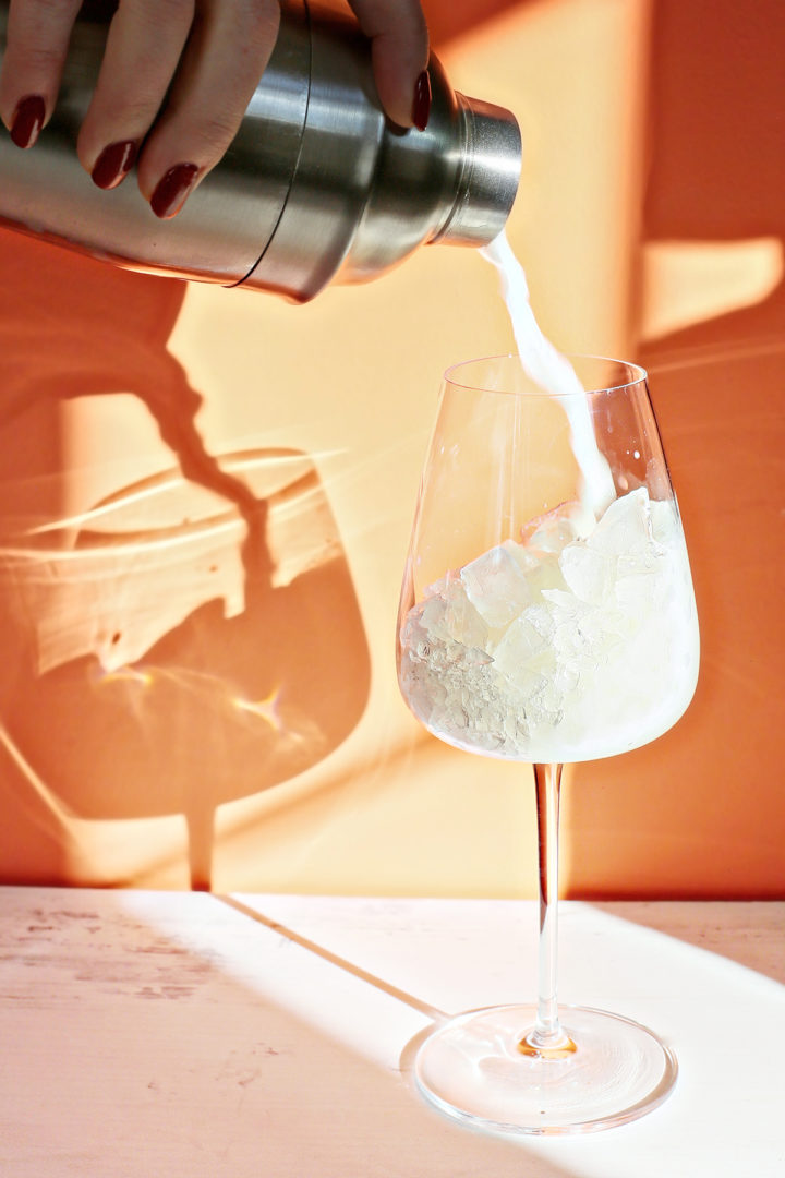 woman pouring a pina colada cocktail into a glass of ice