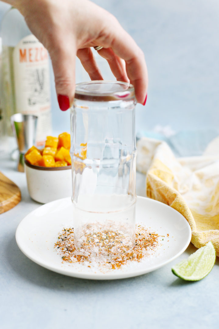 woman rimming a margarita glass with spicy salt