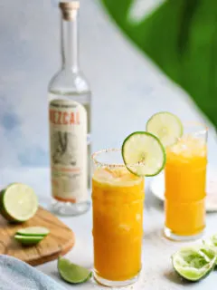 photo of two passionfruit margaritas next to a bottle of mezcal