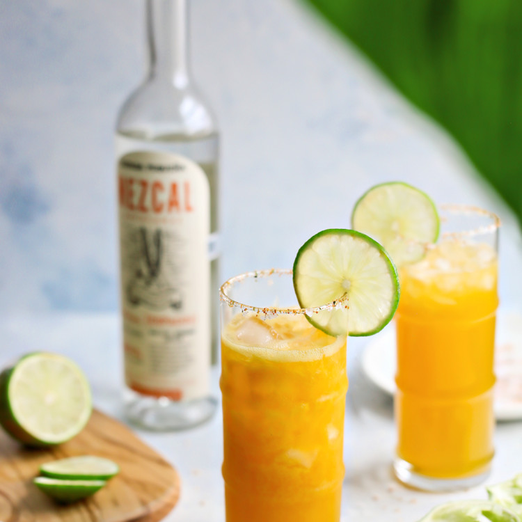 photo of two passionfruit margaritas next to a bottle of mezcal