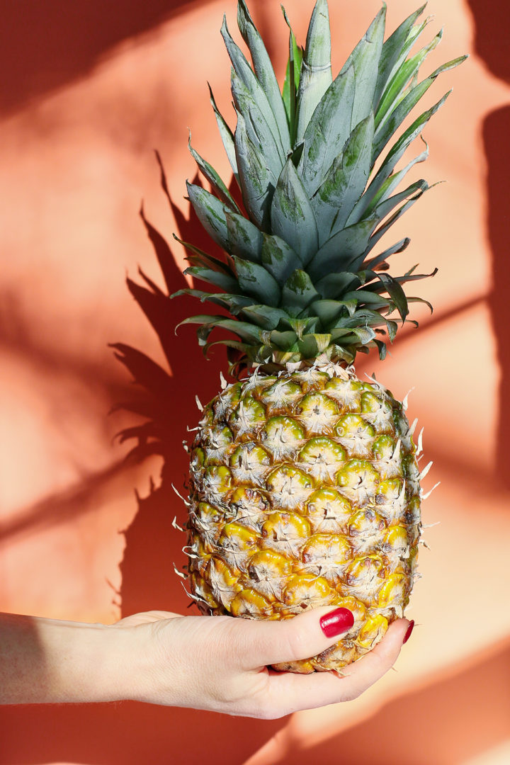 photo of a woman holding a pineapple to use to make a shaken pina colada