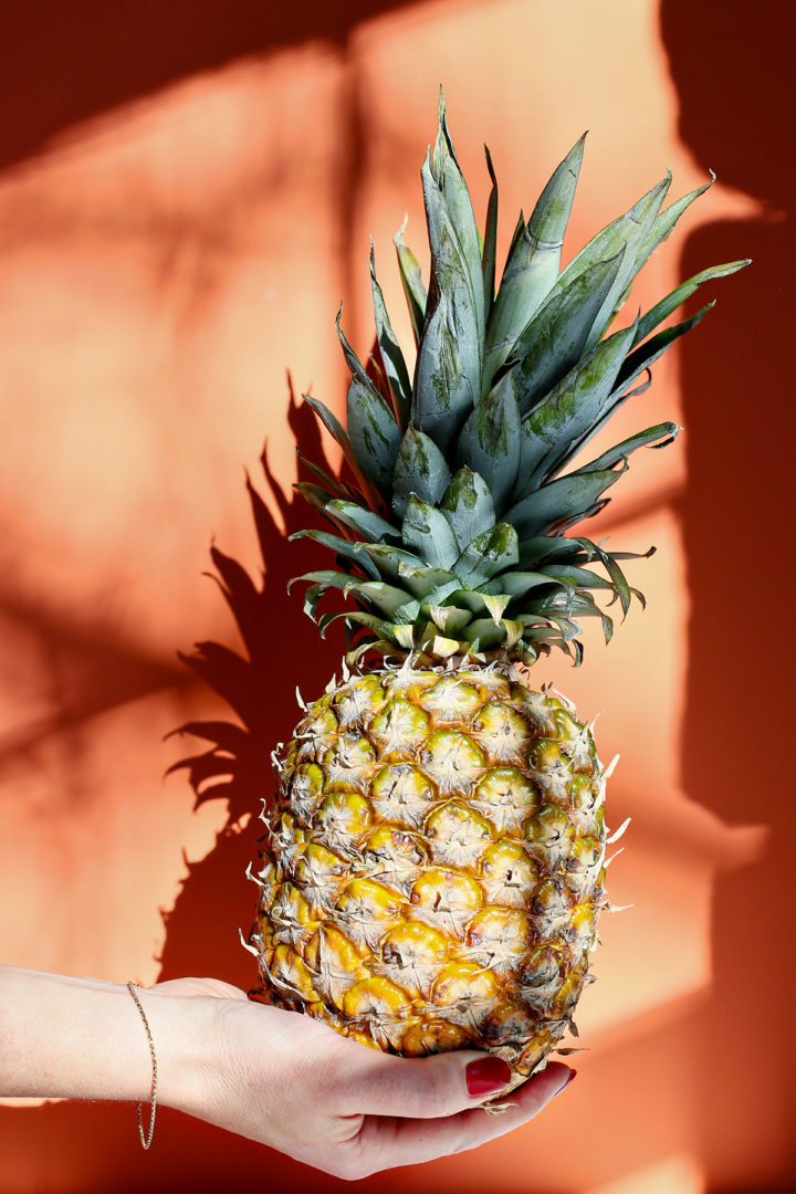 woman holding a fresh pineapple to make this recipe for pina colada