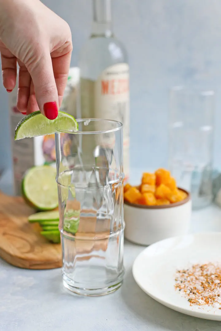 woman rimming a glass with fresh lime to use for a passion fruit cocktail