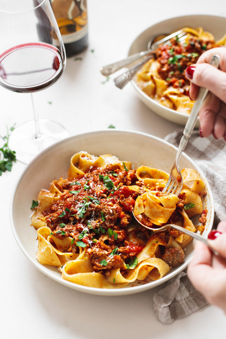 woman twirling tagliatelle pasta on a fork with this bolognese sauce recipe